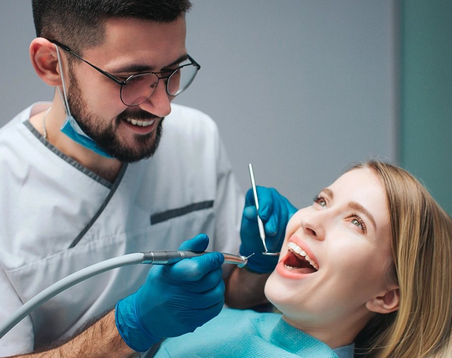 A smiling patient in the chair while an orthodontist works