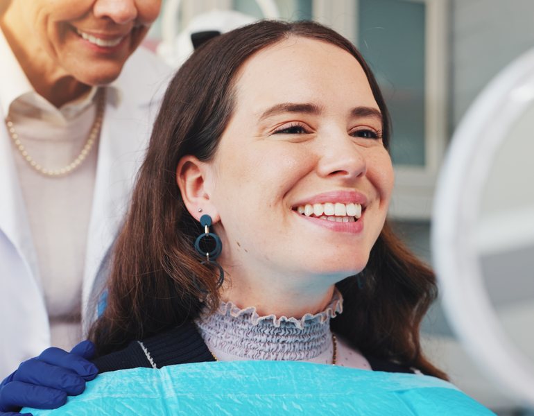 A smiling patient in the dental chair, with the orthodontist behind her