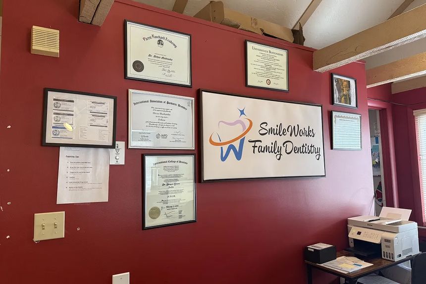 Diplomas and the Smileworks logo on the red reception wall