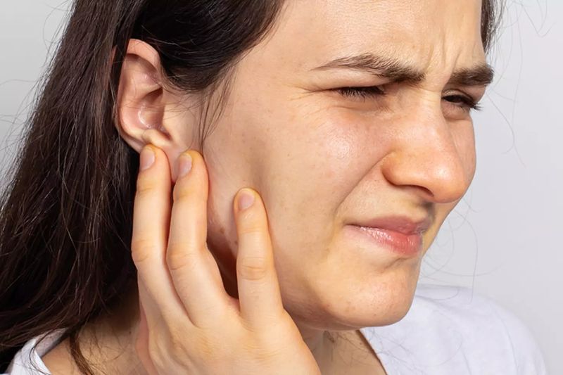 A woman wincing and holding her jaw