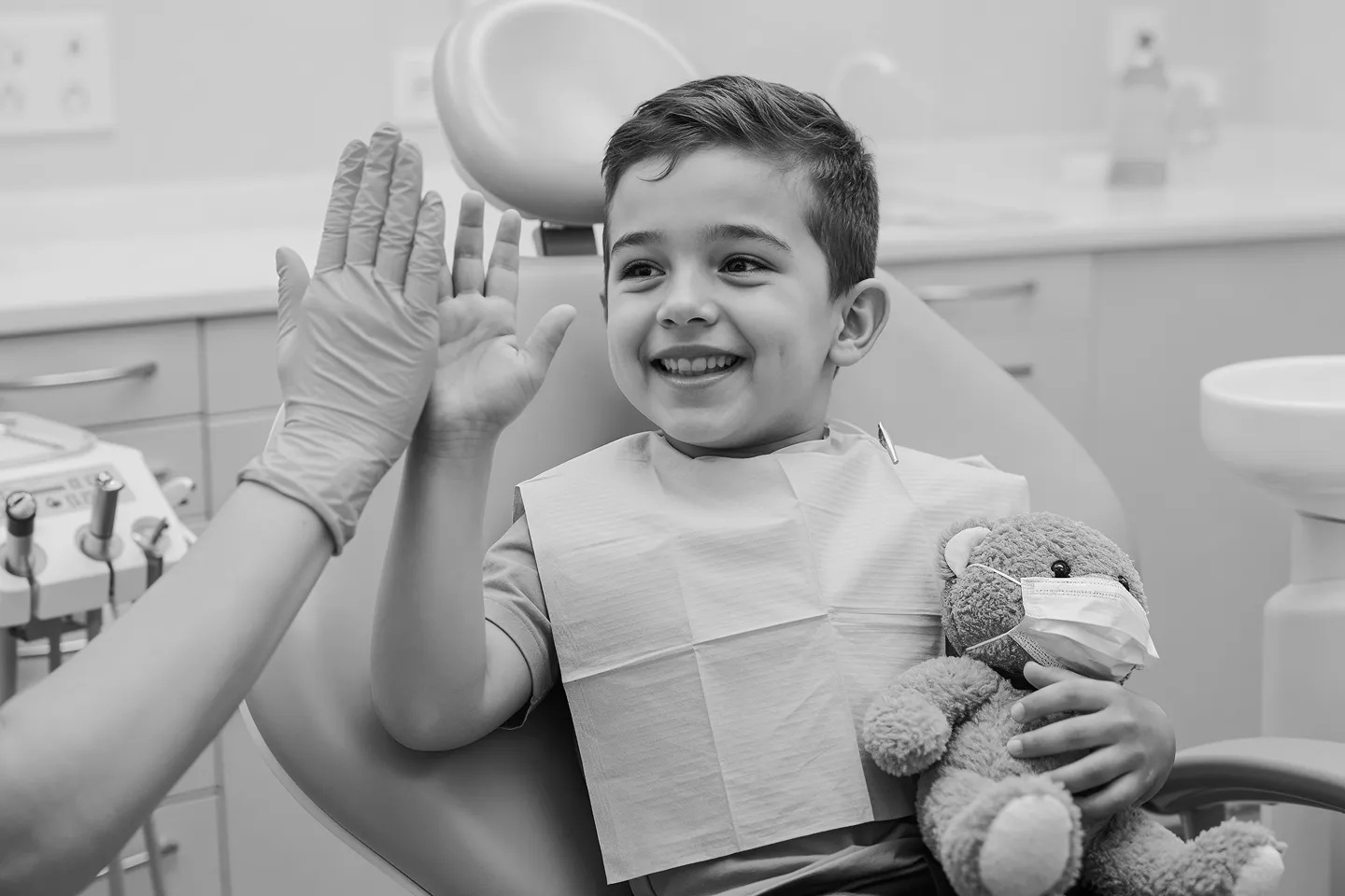 A young boy in the dental chair giving the dentist a high five